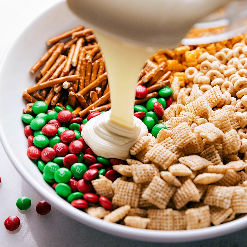 Image of the melted white chocolate being poured over the Christmas Snack Mix.