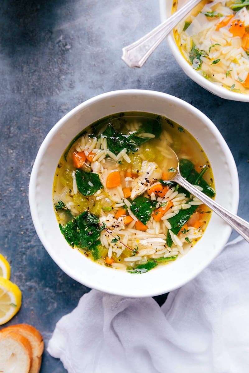 Overhead image of Lemon Chicken Orzo Soup in a bowl, with a spoon in it, ready to be eaten