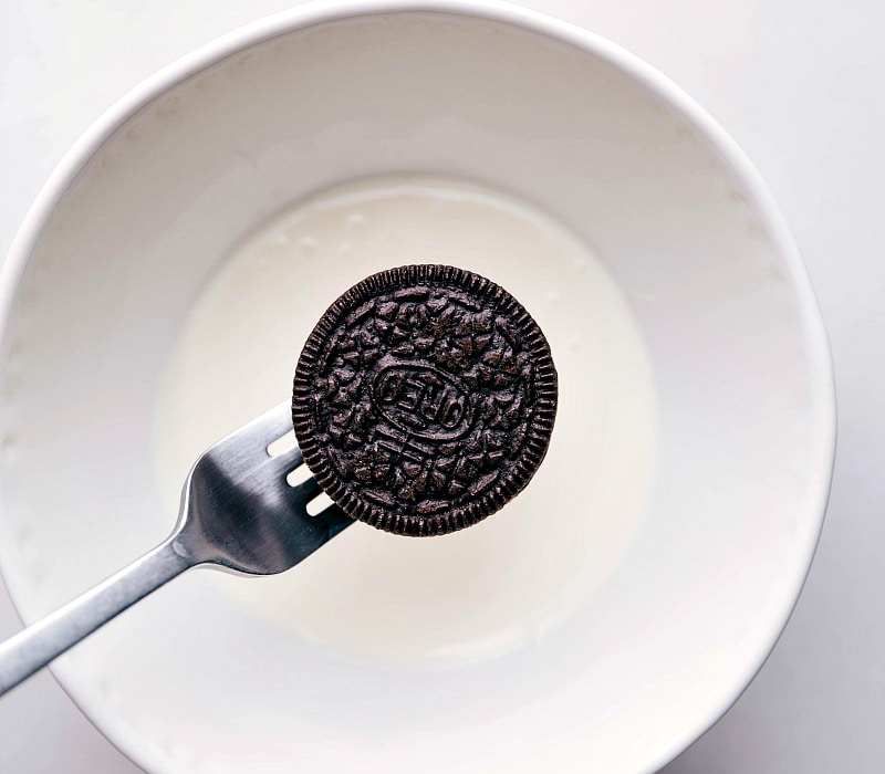 Overhead image of the Oreo being held over the chocolate about to be dipped