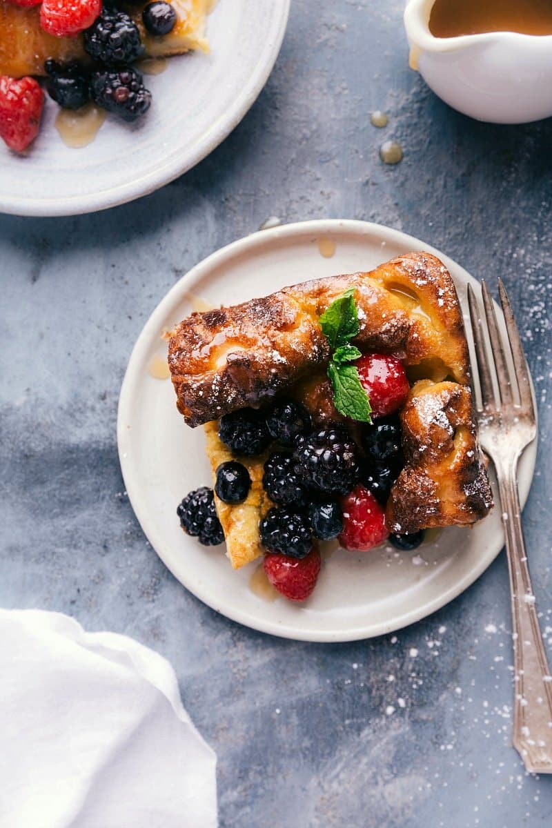 Cut-out piece of the dutch baby german pancake recipe on a plate, topped and ready to eat.