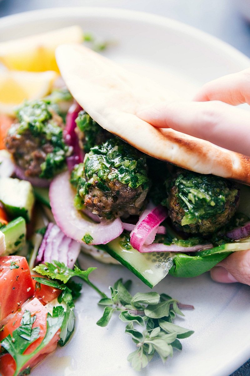 Image of Greek Meatballs being served in a pita with toppings and sauce.