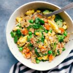 Bowl of quinoa fried rice with colorful vegetables, ready to serve.