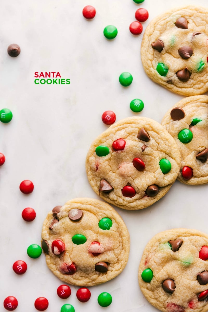 Overhead image of several Santa Cookies, surrounded by red and green candies.