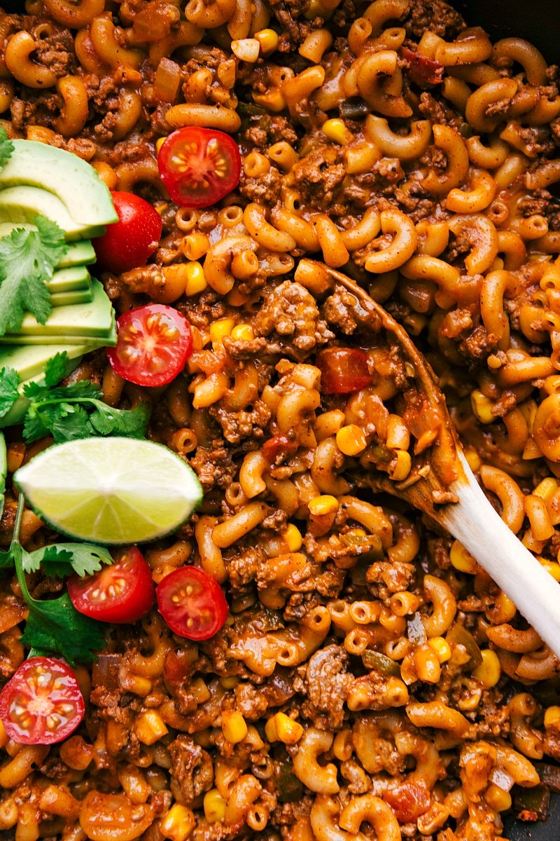 Completed taco pasta dish garnished and ready, with a spoon capturing a hearty serving.