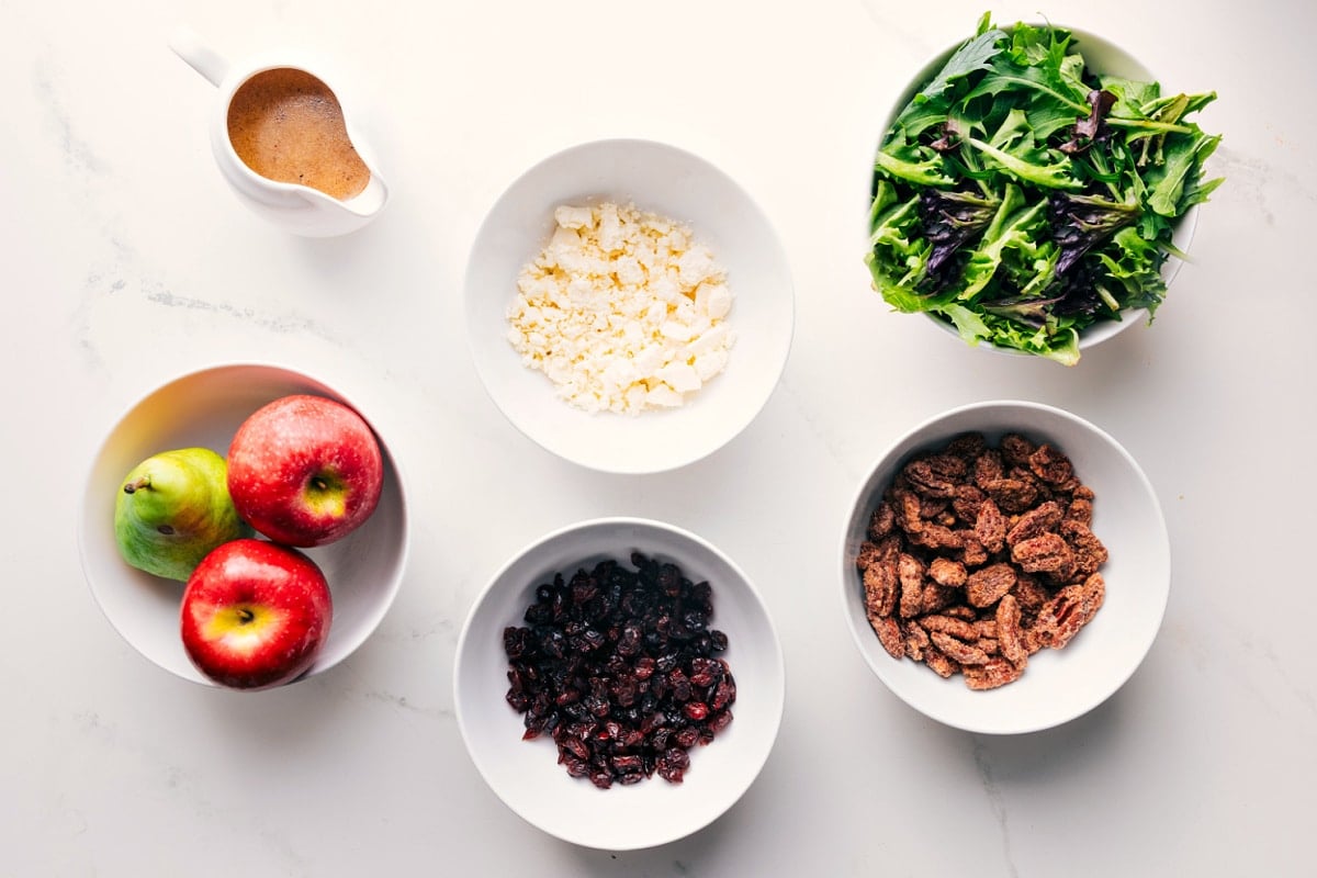Key Ingredients for Crafting Apple Salad: Apple, Pear, Cranberries, and Walnuts All the ingredients in this recipe prepped out for easy assembly including the apples, pear, dried cranberries, pecans, mixed greens, feta, and dressing.