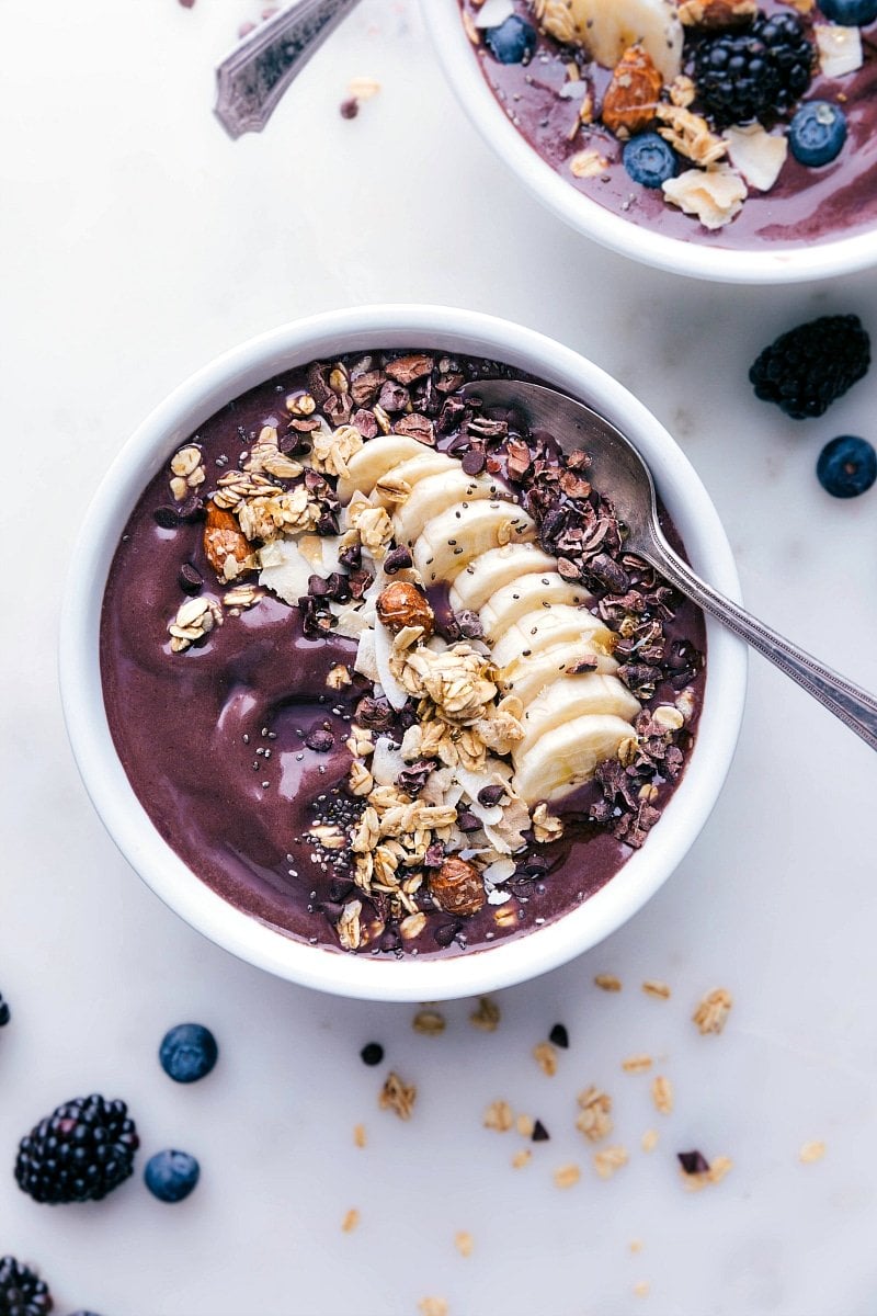 Açaí bowl with almond butter, adorned with various toppings and a spoon on the side, ready to be savored.