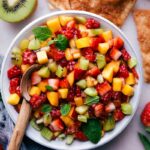 Delicious, fresh fruit salsa in a bowl with a spoon, and cinnamon tortillas on the side.