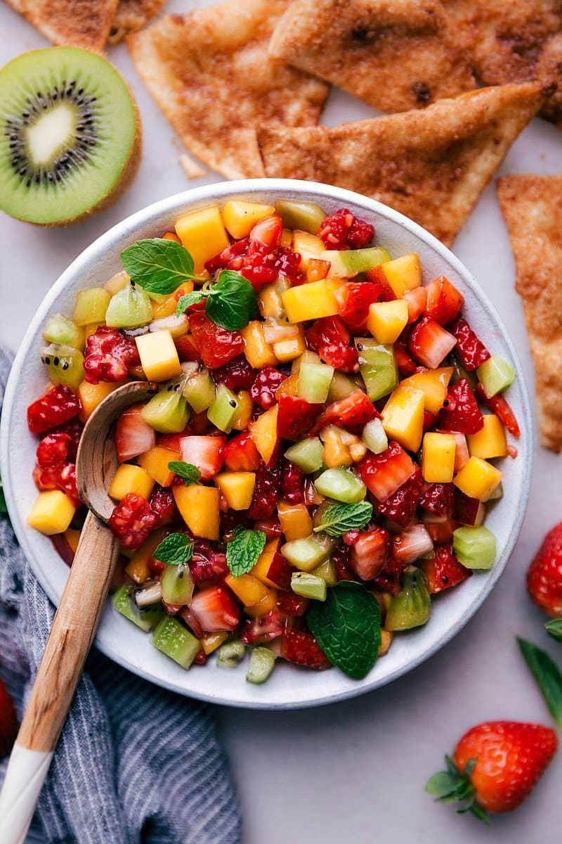 Overhead image of fresh Fruit Salsa in a bowl with a spoon in it and cinnamon tortillas on the side.