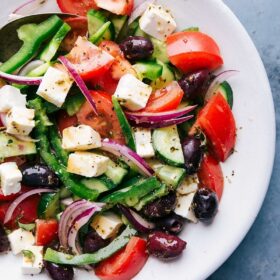 Fresh greek salad in a bowl with tomatoes, olives, feta cheese, and cucumbers.