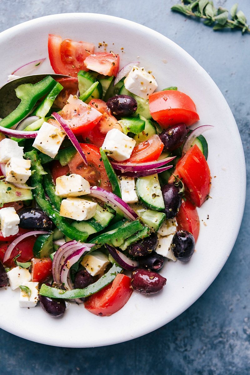 Fresh greek salad in a bowl with tomatoes, olives, feta cheese, and cucumbers.