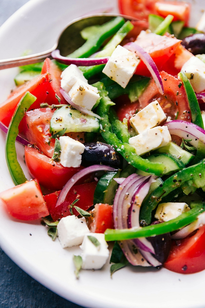 Completed greek salad recipe drizzled in dressing, ready to serve.