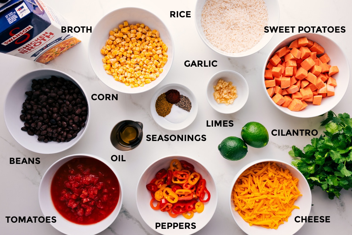 Ingredients for One-Skillet Sweet Potato Burrito Bowl All the ingredients in this recipe prepped out for easy assembly including the broth, beans, tomatoes, oil, peppers, cheese, cilantro, limes, sweet potatoes, rice, garlic, seasonings, and corn.