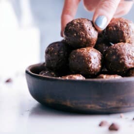 Bowl filled with delectable chocolate energy bites, a hand reaching in to grab a delightful bite.