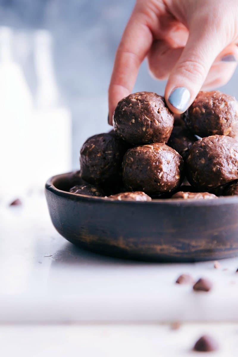 Image of Chocolate Energy Bites in a bowl with a hand reaching in to grab them.