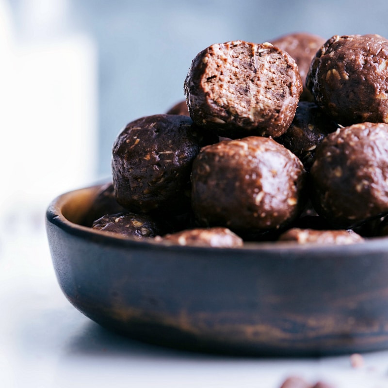 Bowl filled with tempting chocolate energy bites, one with a missing bite, showcasing their delectable nature.