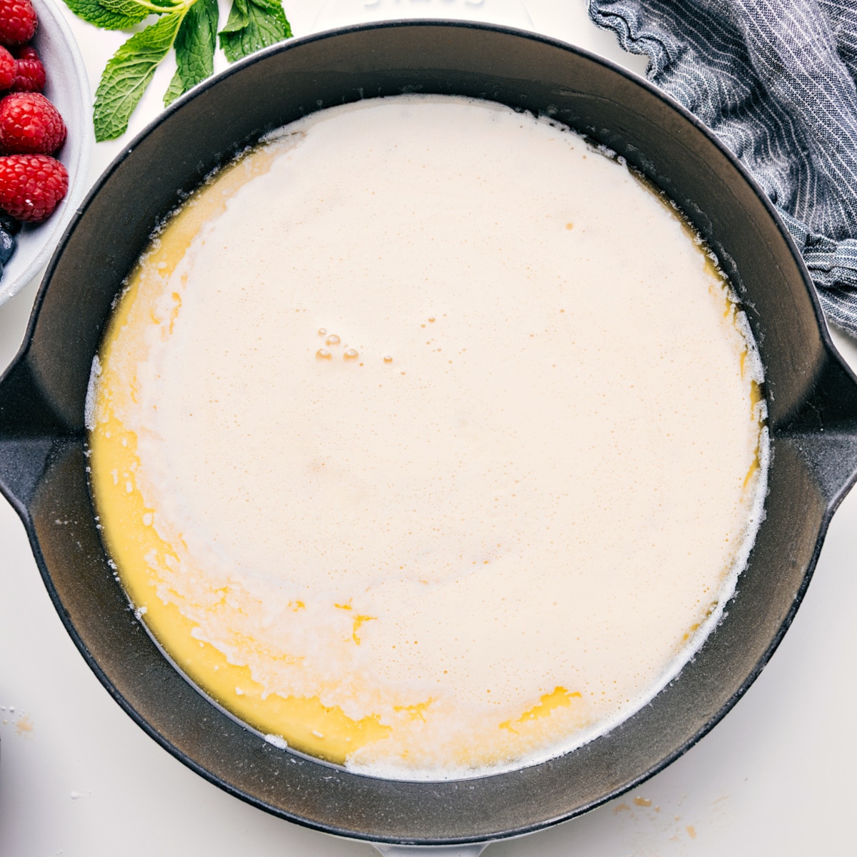The dutch baby batter poured into a heated and buttered skillet to be baked.