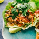 Plate of peanut chicken lettuce wraps, featuring vibrant lettuce cups filled with savory chicken and peanut sauce.