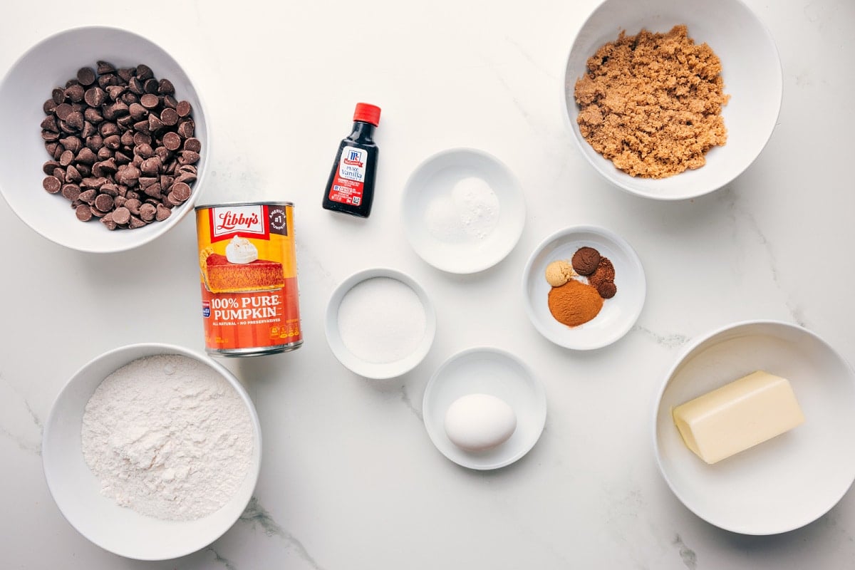All the ingredients in this recipe prepped out for easy assembly including the chocolate chips, flour, pumpkin, vanilla, baking agents, butter, spices, and brown sugar.