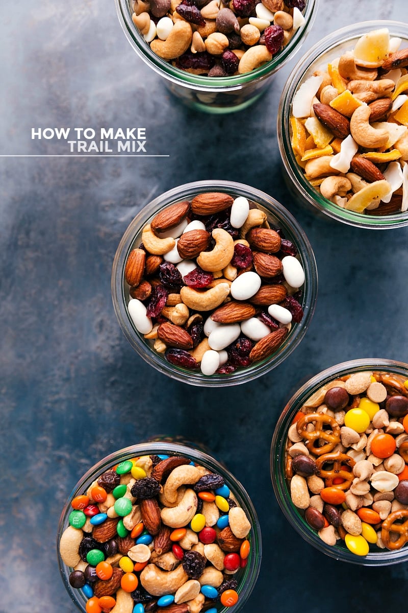 Assortment of five different types of delicious trail mix in clear glass jars.