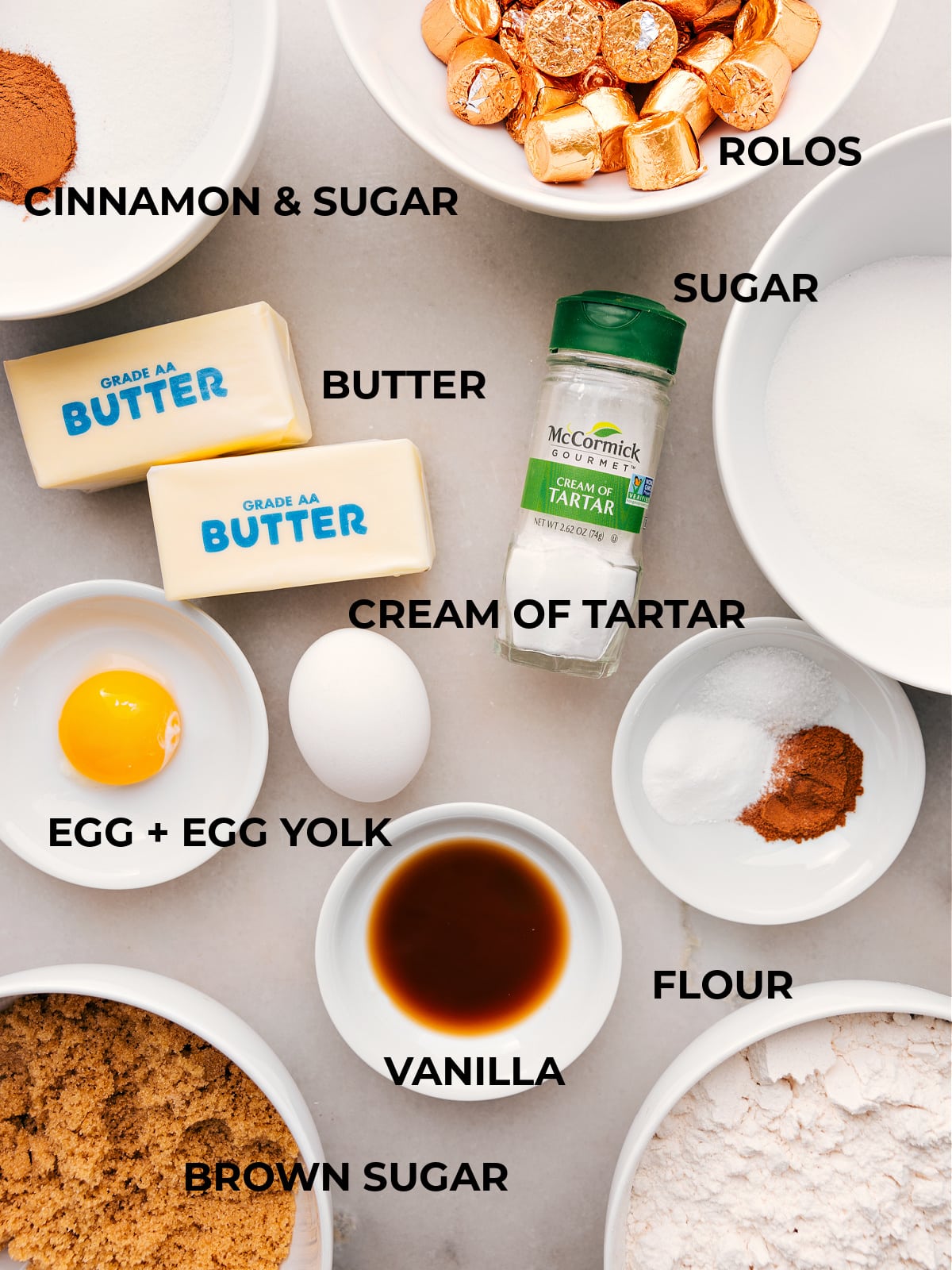 An assortment of baking ingredients, featuring butter, cinnamon and sugar, flour, and more.