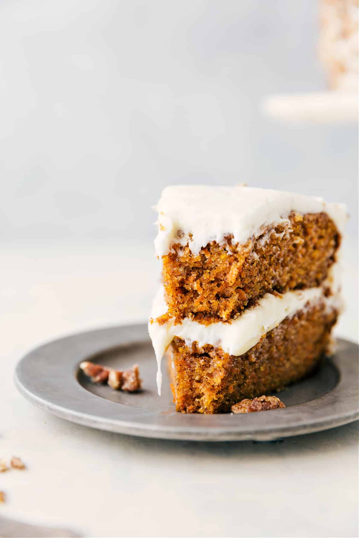 A slice of carrot cake with a bite taken out, showing the rich layers inside.
