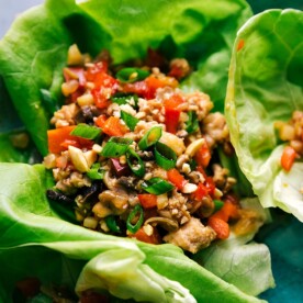 Chicken lettuce wrap filled with meat and veggie mixture, garnished and ready to eat.