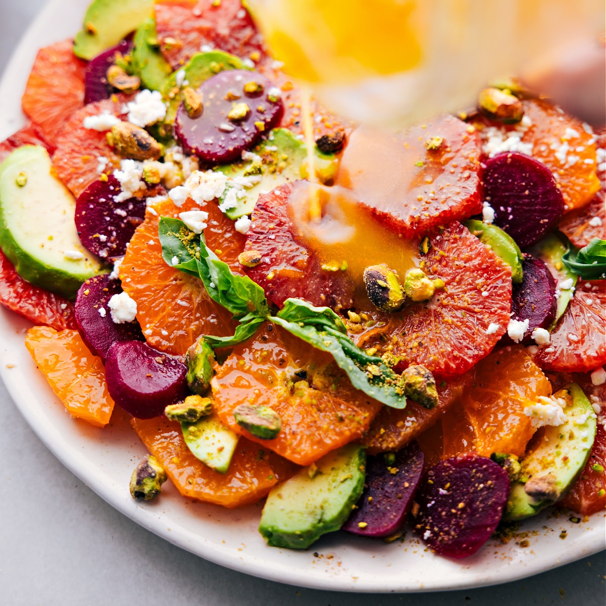 The dressing being poured over the citrus salad recipe.