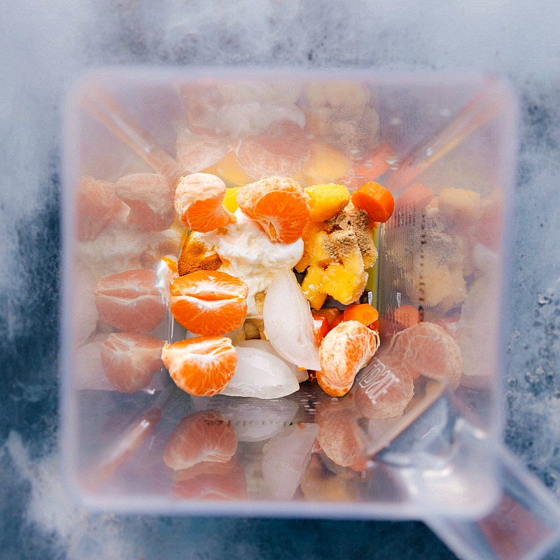 Fruit and ice in a blender jar, ready for a refreshing blend.