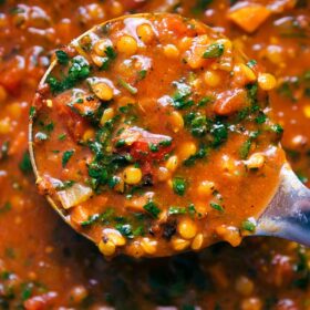 A ladle containing a scoop of lentil soup, ready to be served.