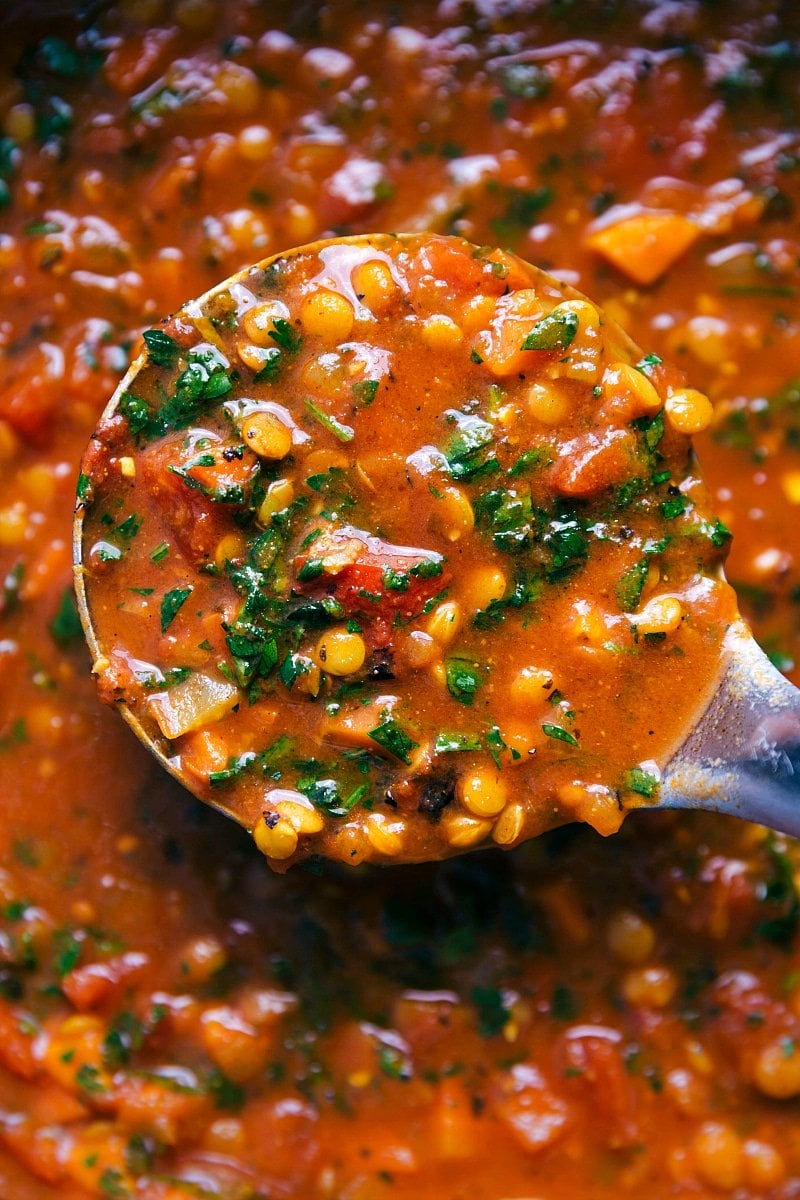 A ladle containing a scoop of lentil soup, ready to be served.