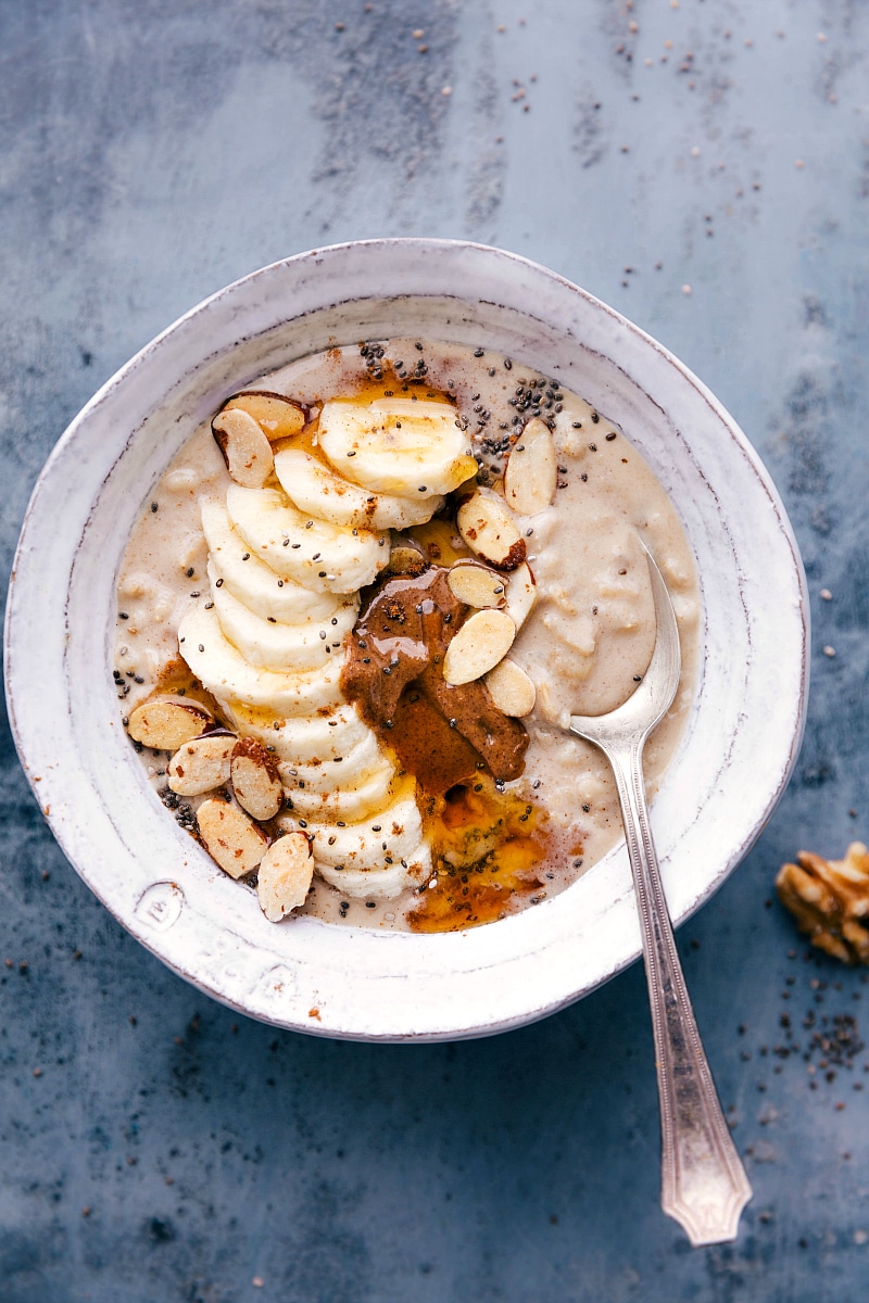 Overhead image of a bowl of peanut butter and banana breakfast with fresh bananas, sliced almonds, and fresh peanut butter on top.