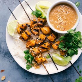 Skewers of peanut sauce chicken, artfully presented on a plate with a side of luscious peanut sauce.