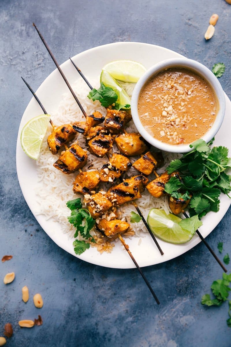 Skewers of Peanut Sauce Chicken, served on a plate with a bowl of peanut sauce.