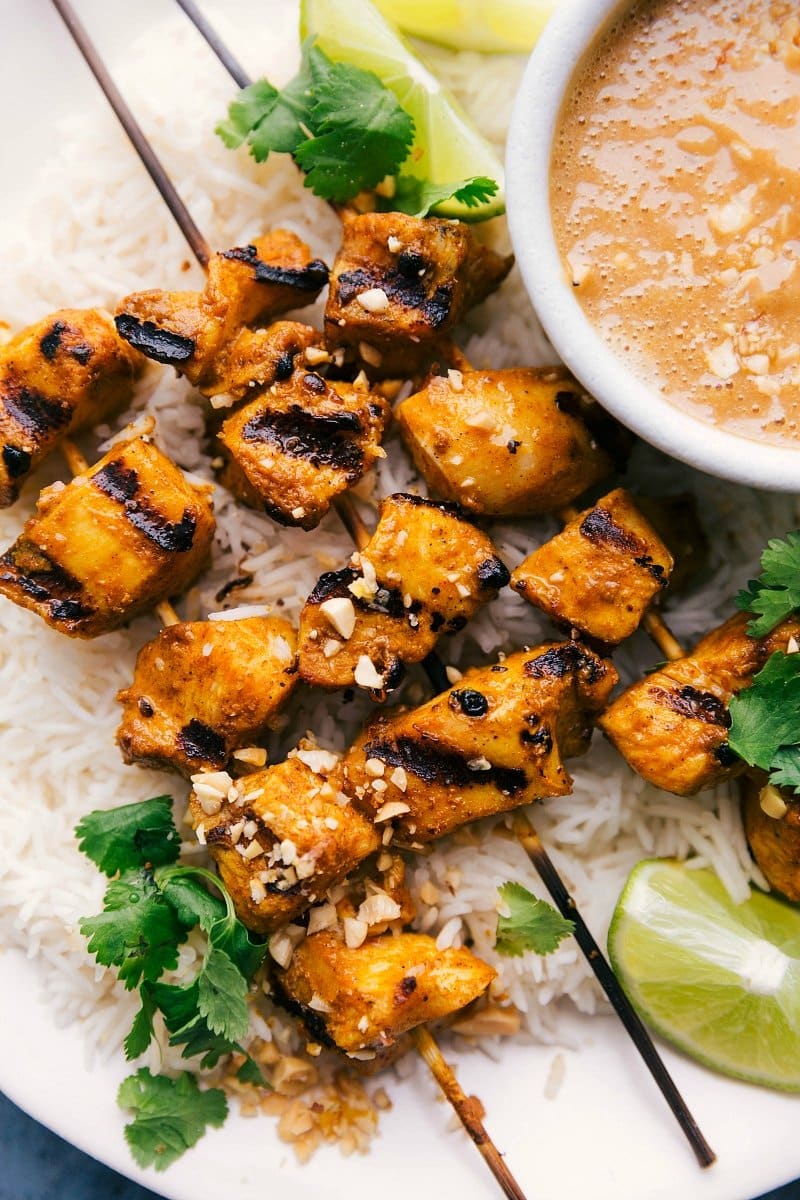 Grilled chicken with peanut sauce, served alongside a bowl of flavorful sauce.