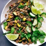 Beef larb accompanied by rice, with lime and cilantro garnishes.