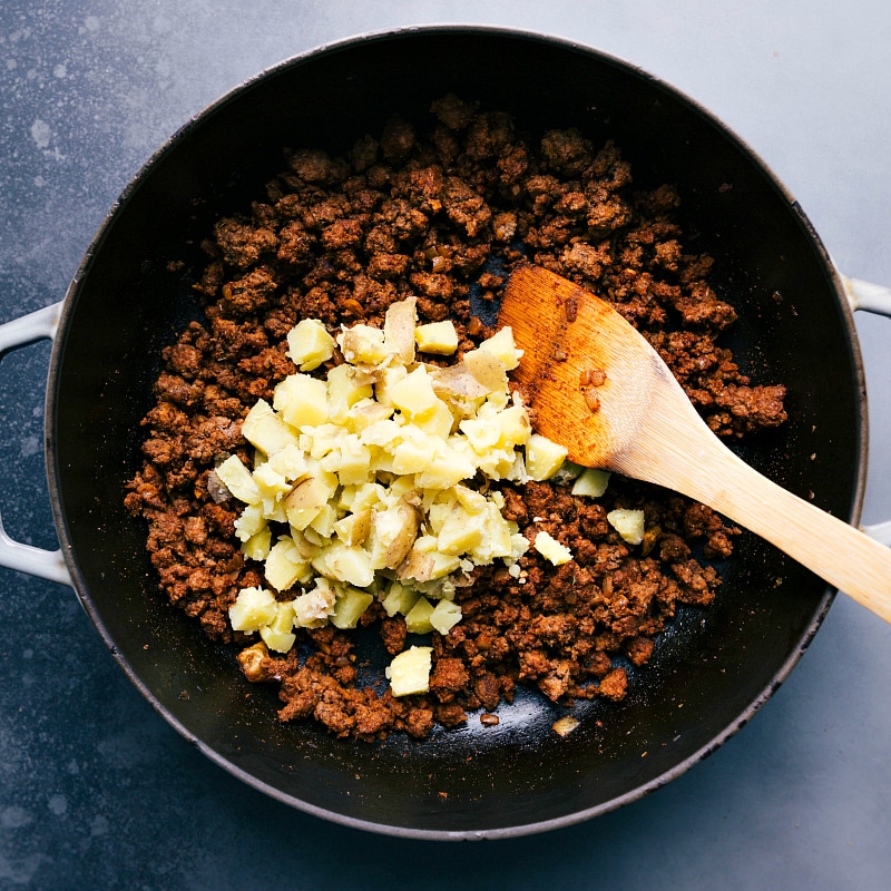 Image of the potatoes being added to the meat.