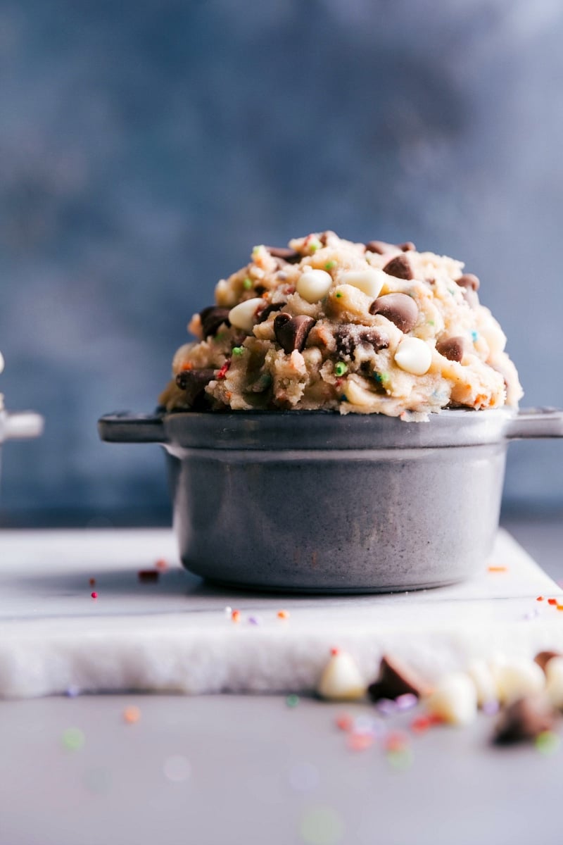 Creamy edible cake batter dough in a bowl, enriched with white and milk chocolate chips and colorful sprinkles.