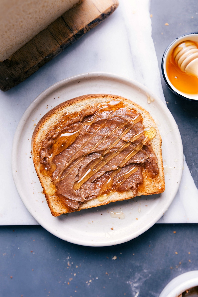 A slice of bread topped with fresh honey and a dollop of honey butter.