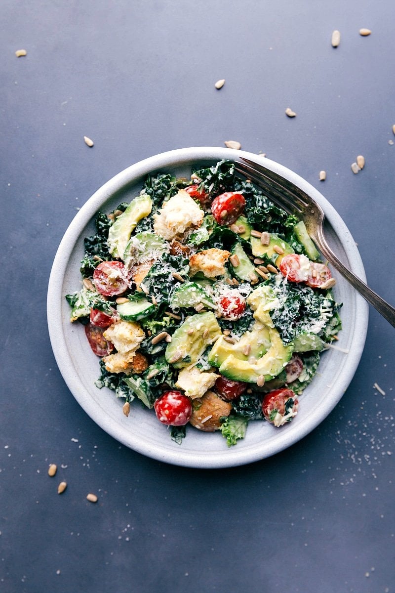 Fresh kale avocado salad, garnished and ready to eat, featuring lush greens, creamy avocado slices, and added toppings.