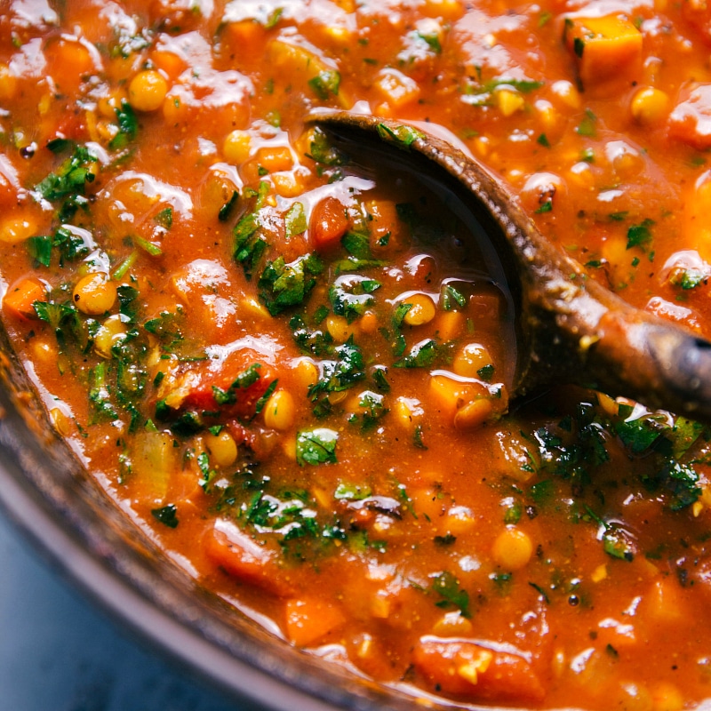 Overhead image of Lentil Soup in the pot with a wooden spoon stirring it.