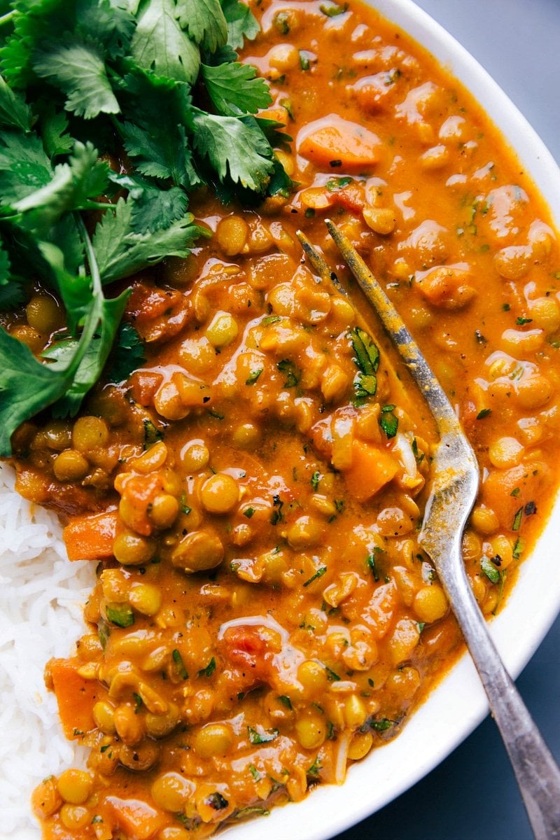 Overhead image of Lentil Curry with a fork beside it, and fresh cilantro and rice on the side.