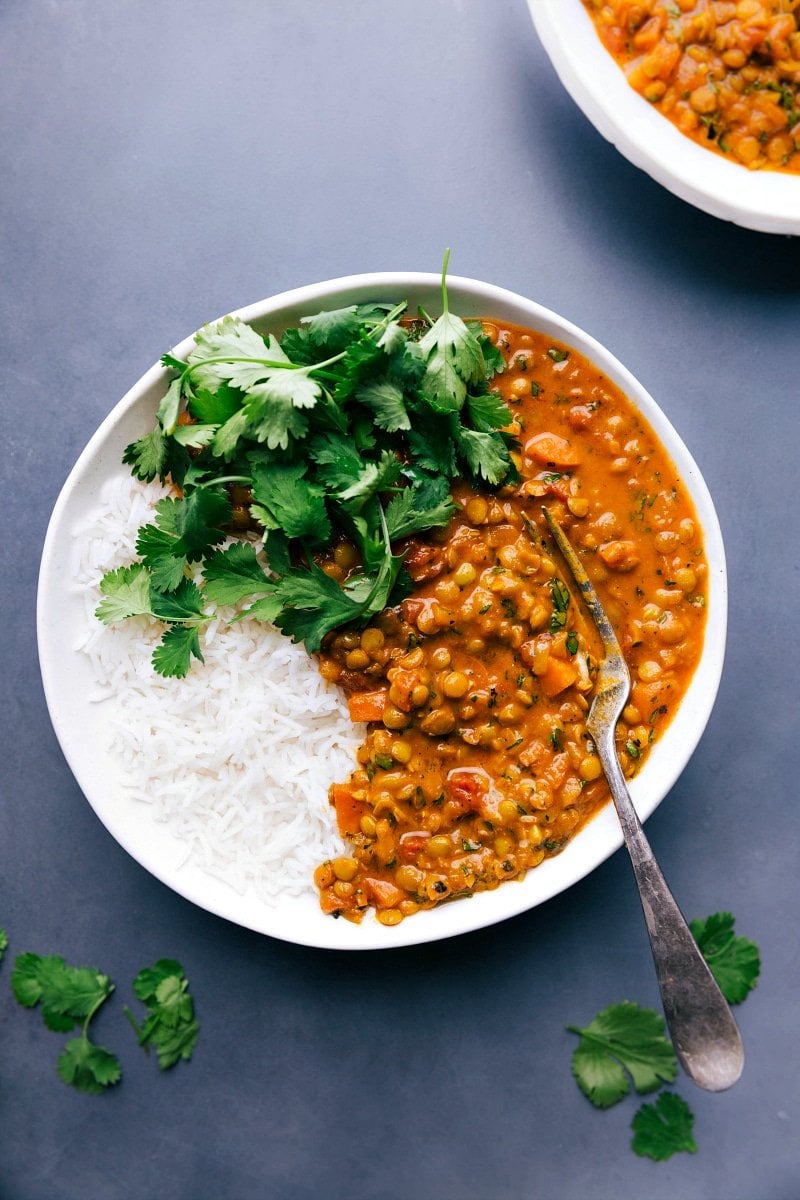 Overhead image of Lentil Curry in a bowl, with t.he rice on the side and fresh cilantro on top