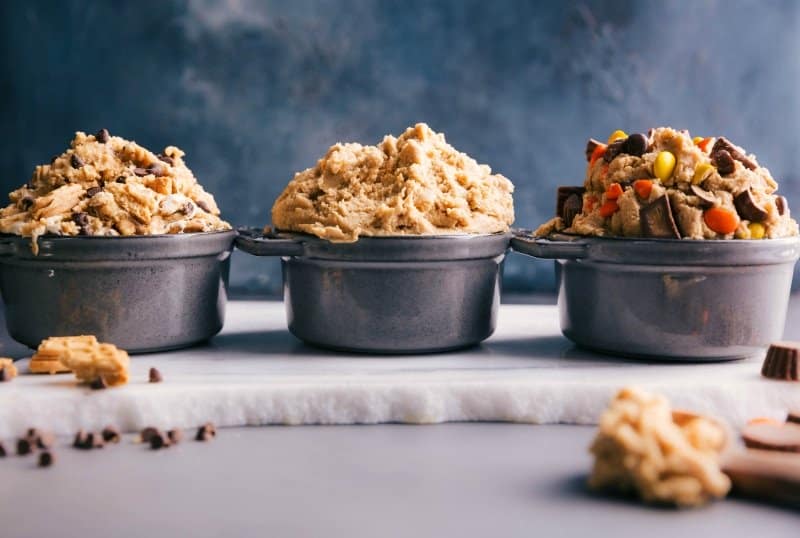 Three bowls of edible cookie dough in different flavors: classic chocolate chip, s'mores, and peanut butter cup.