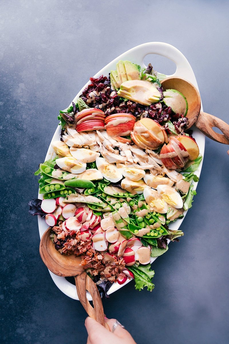 Overhead view of a large serving platter filled with Cobb salad, featuring meats, veggies, fruit and Creamy Balsamic Dressing.