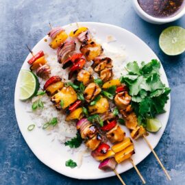 Freshly grilled teriyaki chicken skewers served on a bed of rice, garnished with lime, cilantro, and toasted coconut.