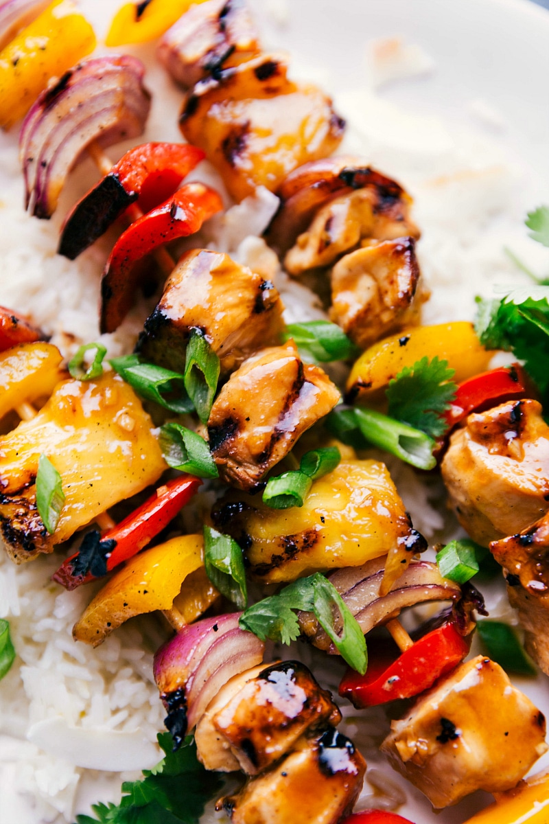 Delicious chicken teriyaki on skewers served over a bed of rice, topped with green onions.