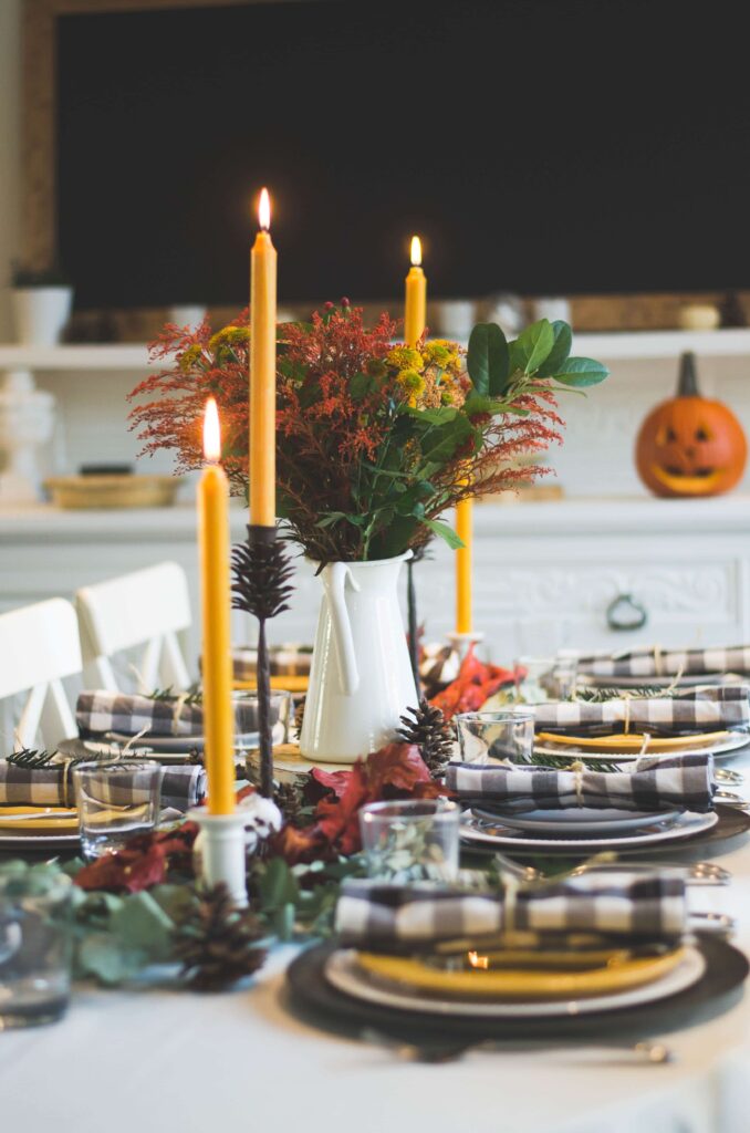 A Thanksgiving tablescape with plates, napkins, candles and seasonal flowers