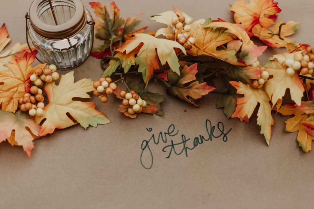 A collection of fall foliage with the message saying give thanks.