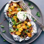Baked potato foil pack with sour cream and chives, a hearty meal ready to enjoy.