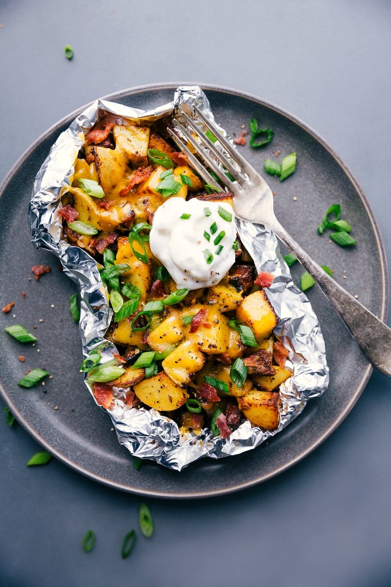 Overhead image of Baked Potato Foil Pack dinner with sour cream and fresh chives on top.